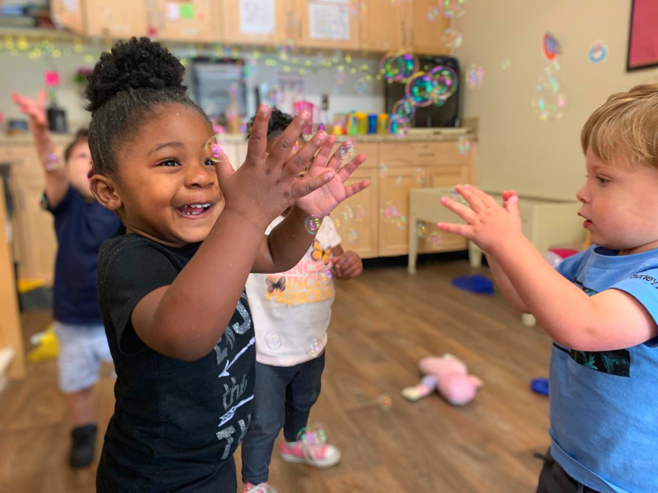 Two children playing with bubbles in a classroom