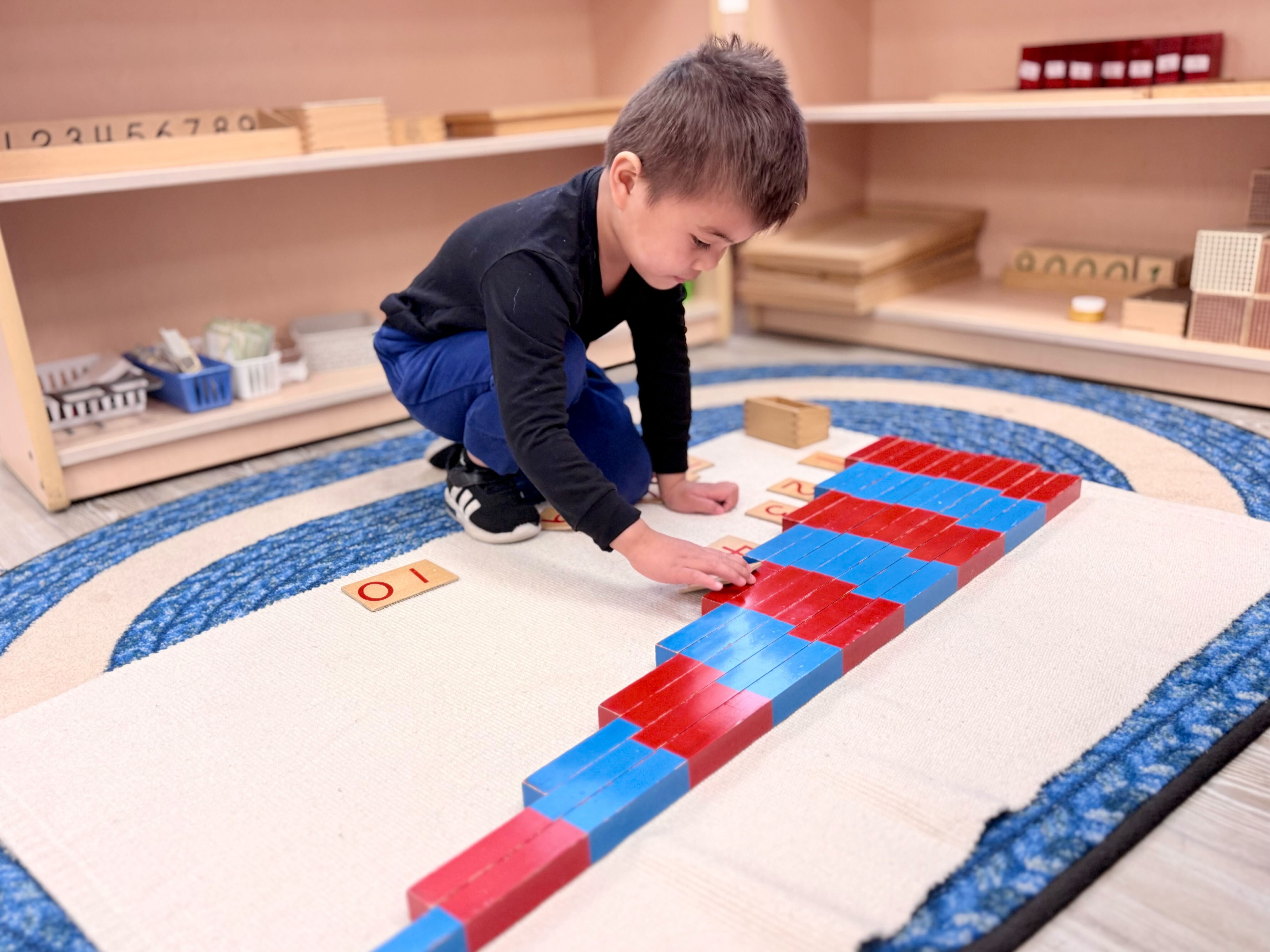 Child playing with red and blue counting rods on a mat