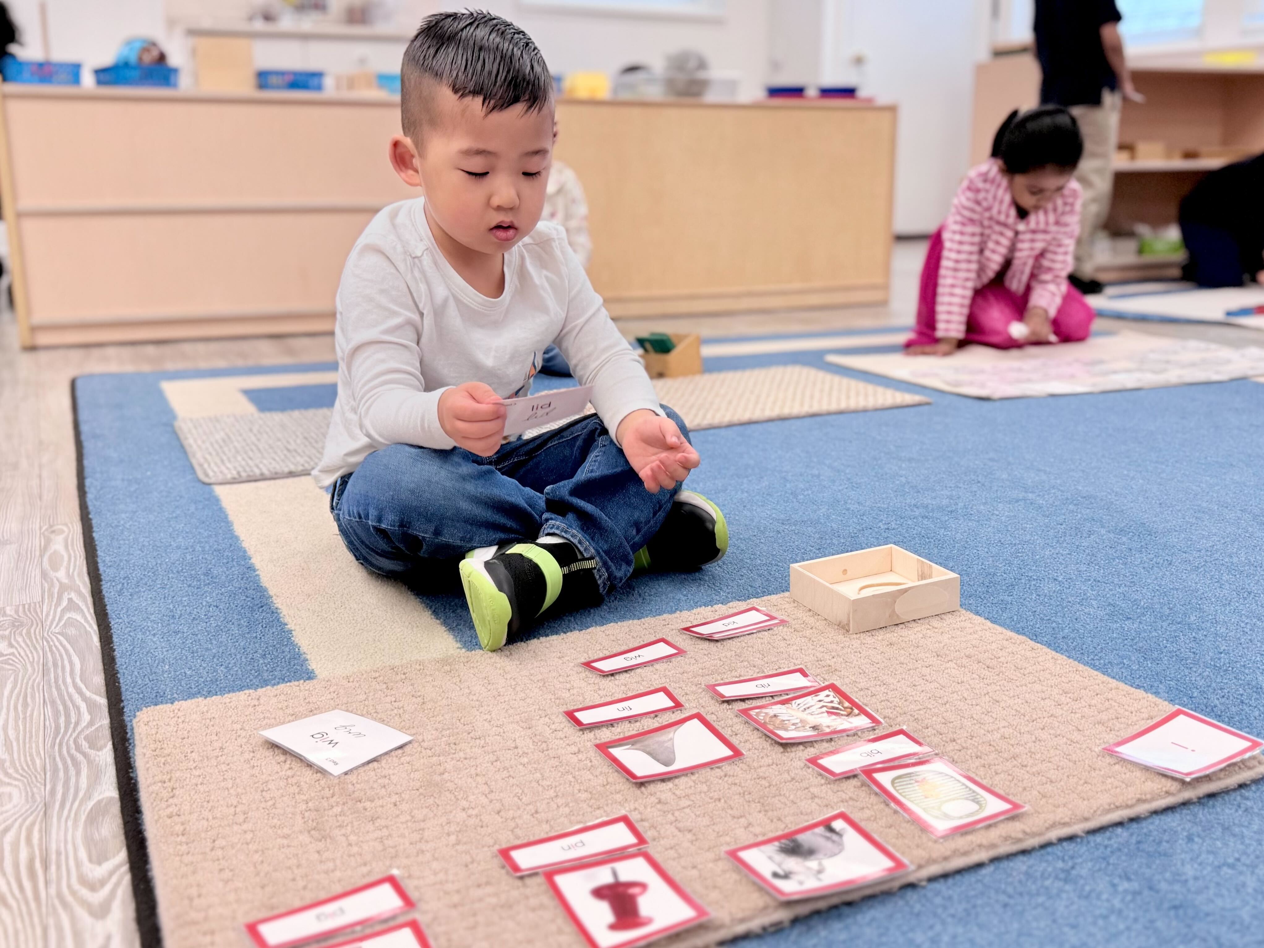 Child sitting on classroom floor matching word and picture cards