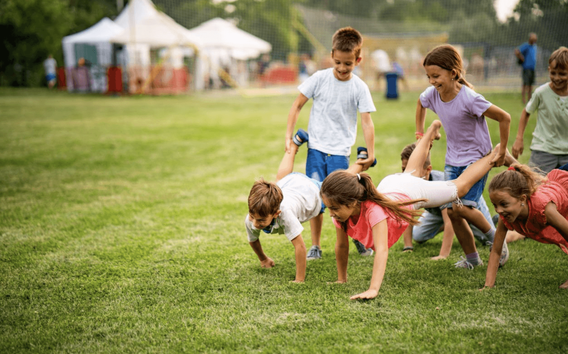Children playing wheelbarrow race on grass