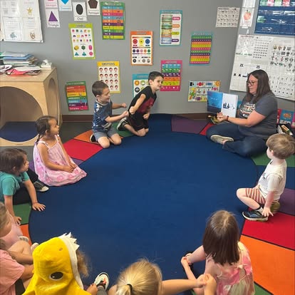 Adult reading a book to children sitting in a circle on the floor