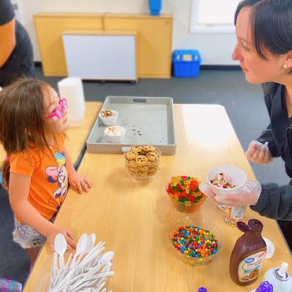 Person and child at a table with dessert toppings
