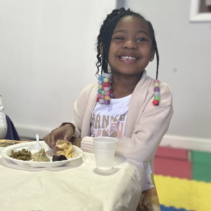 Child sitting at a table with a plate of food