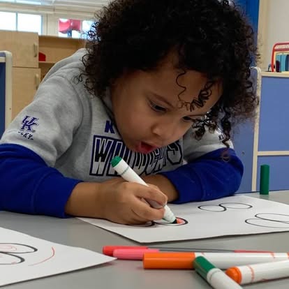 Child coloring on paper with a marker
