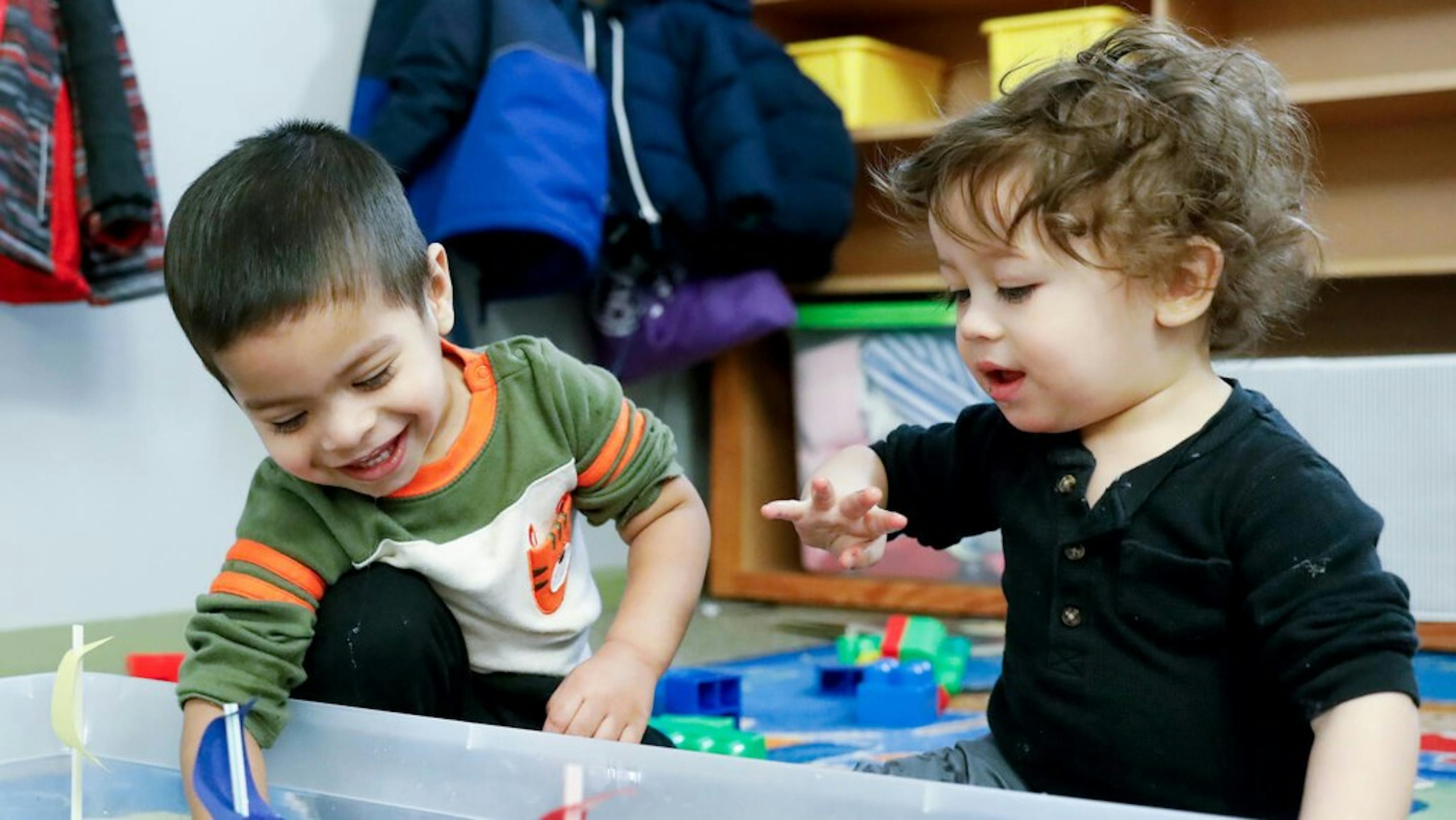 Two children playing with toys in a container
