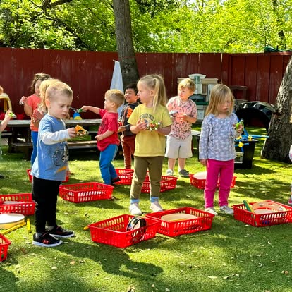 Children playing outdoors with red baskets on a grassy area
