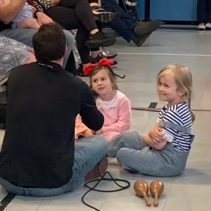 Person and two children sitting on the floor with maracas