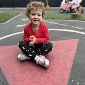 Child sitting cross-legged on a red mat