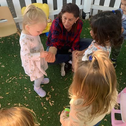 Adult person interacting with children on grass