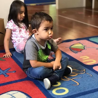 Two children sitting on a colorful rug