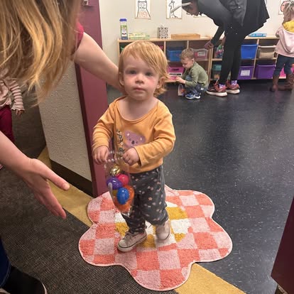 Child standing on a rug holding a bag of ornaments