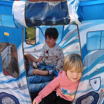 Two children playing inside a blue play tent