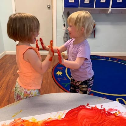 Two children with paint on their hands playing together