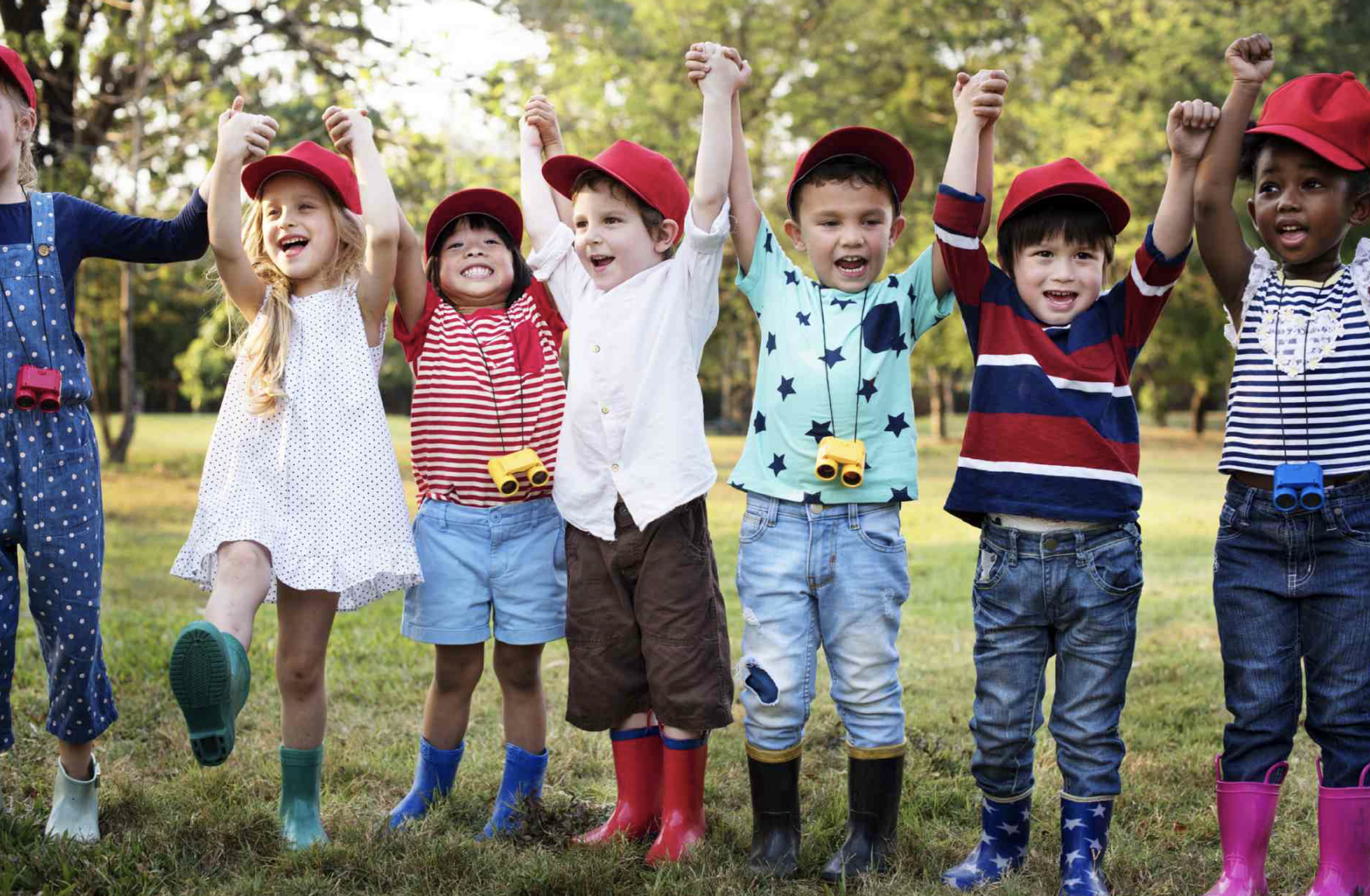 Group of children with arms raised in a field