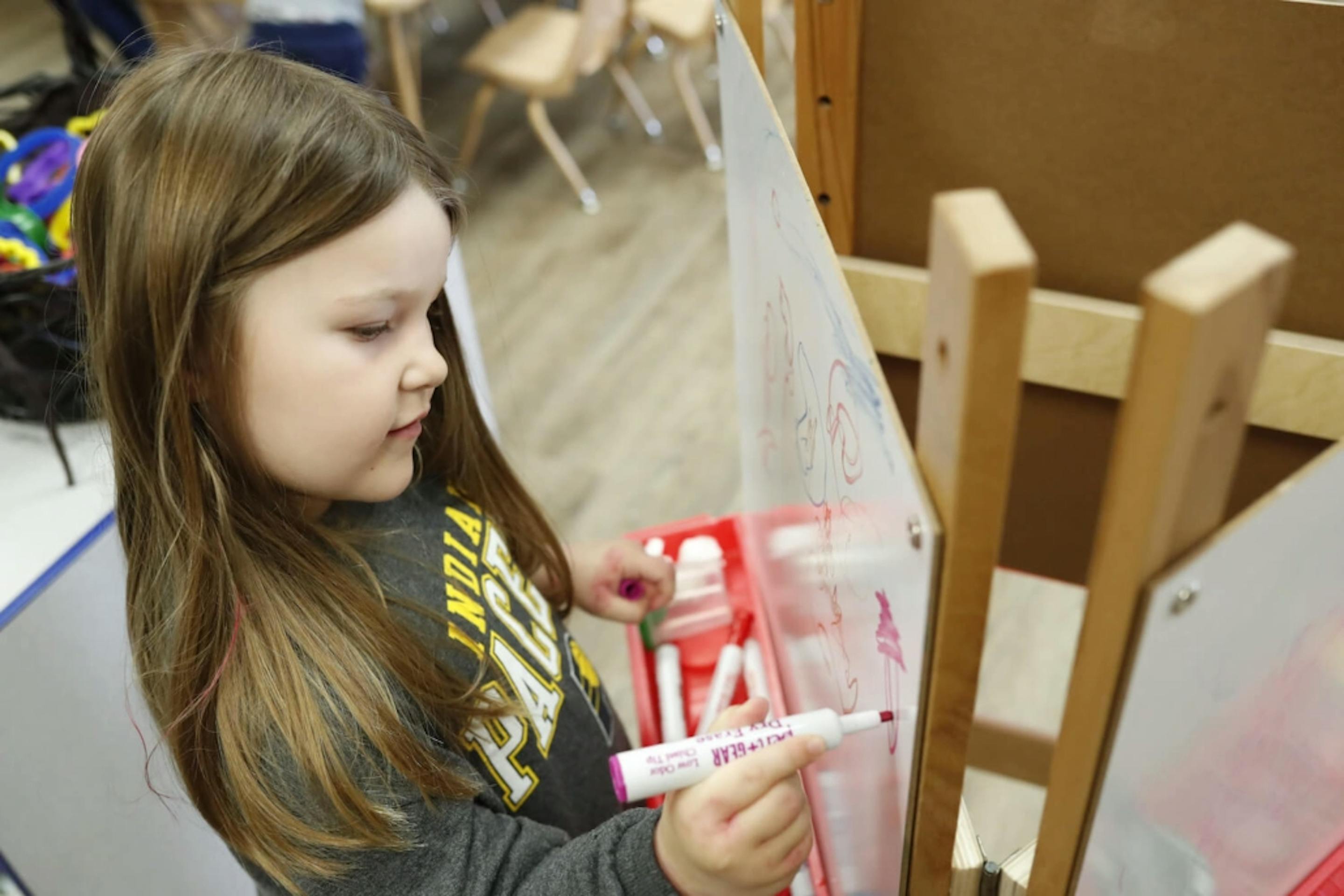 Child drawing on an easel with a marker