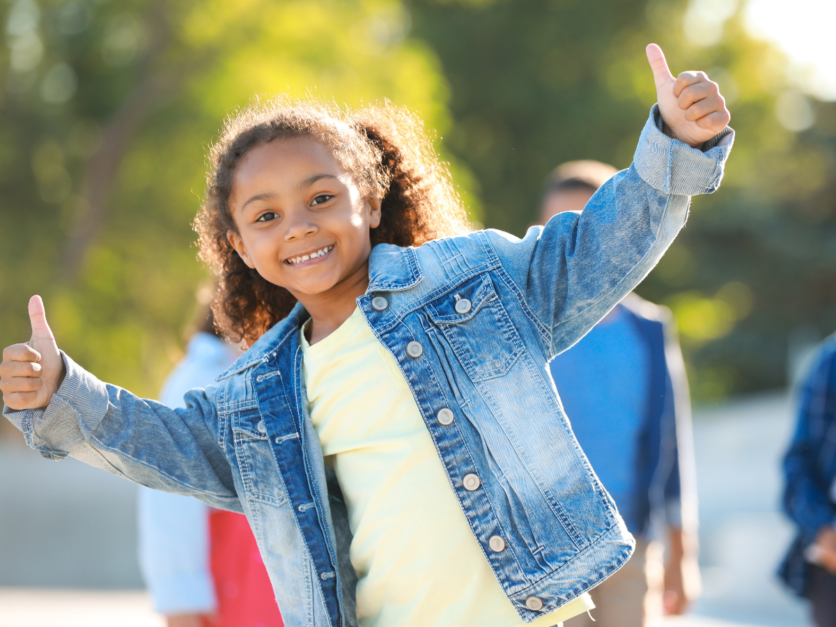 Child smiling and giving a thumbs up sign