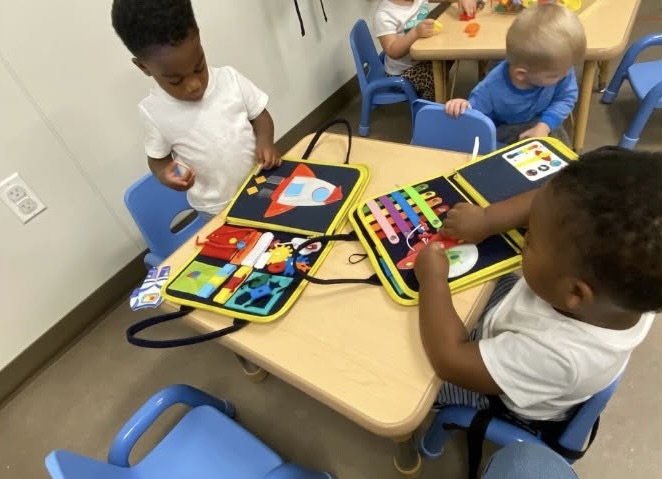 Children sitting at a table playing with educational activity boards