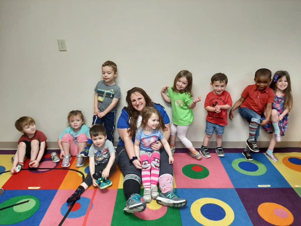 A person sitting on a colorful rug with a group of children