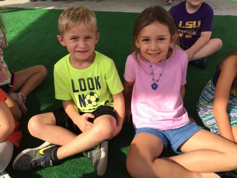 Two children sitting on artificial grass