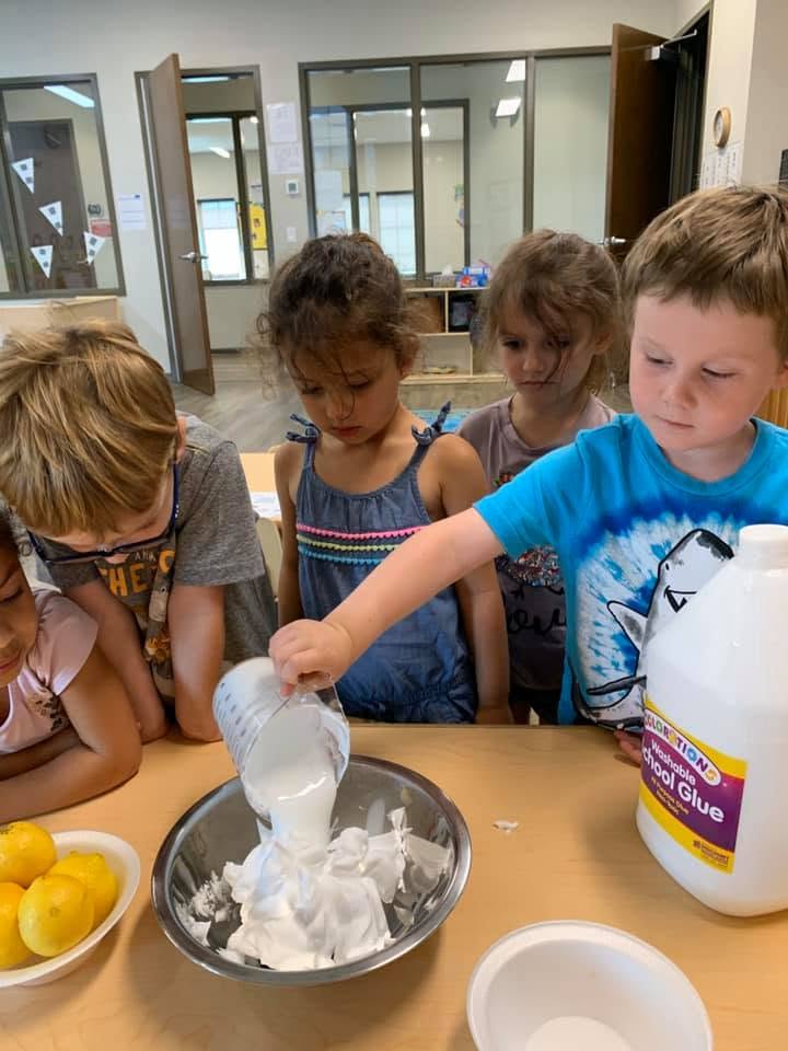 Children pouring glue into a mixing bowl