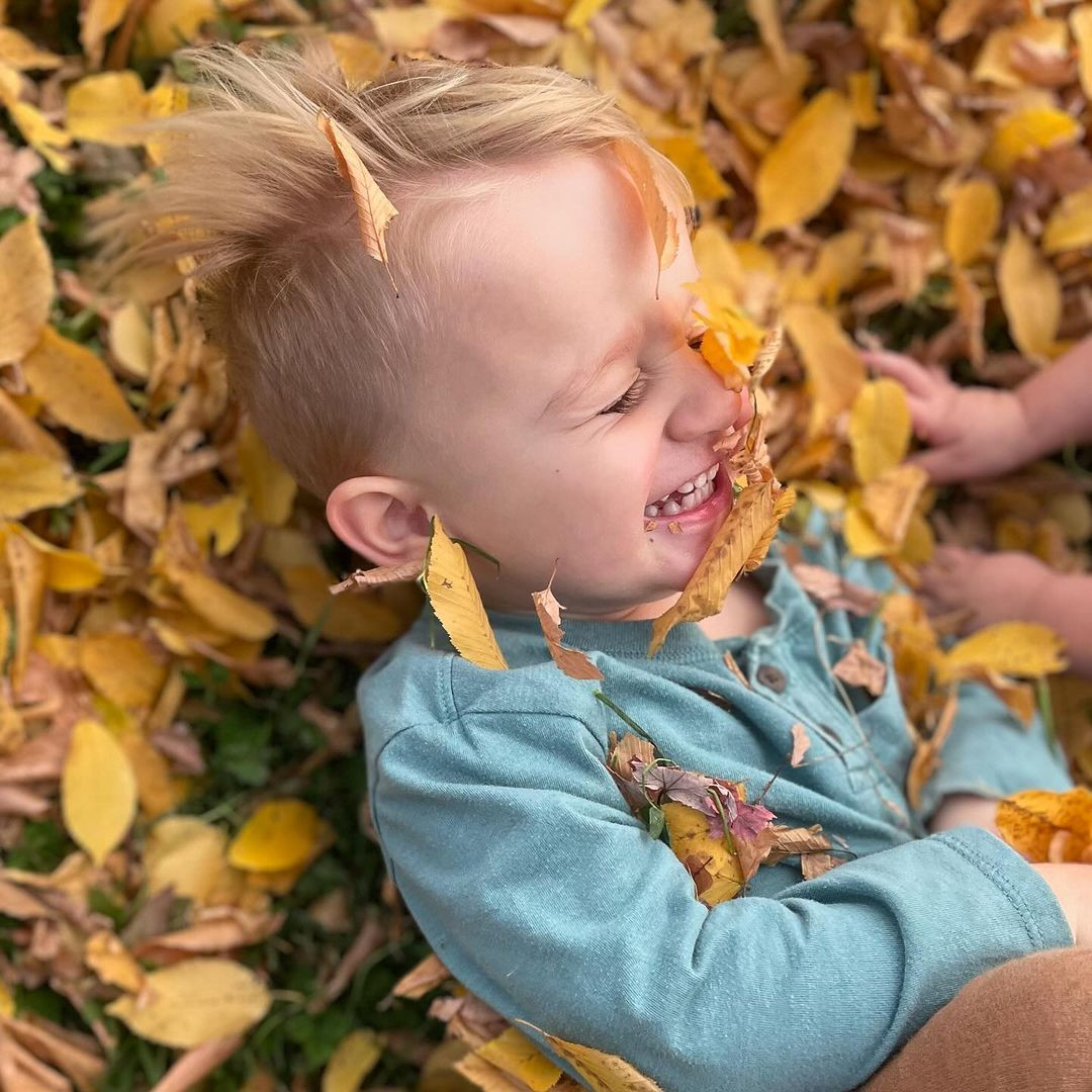 Child lying in a pile of yellow leaves