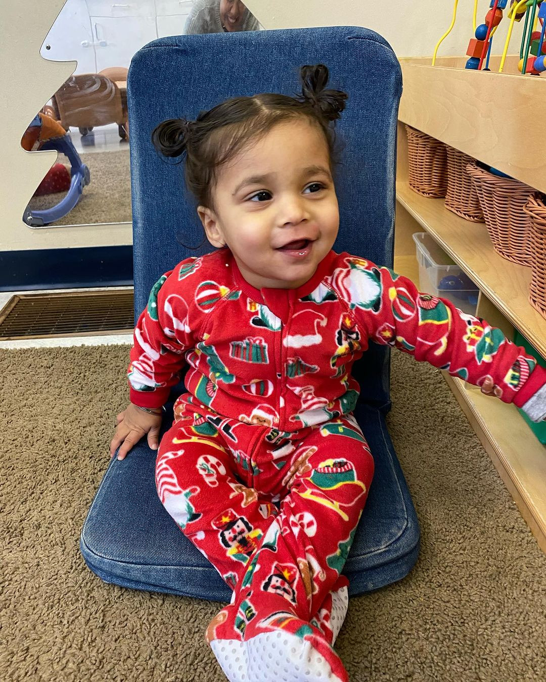 Child in red pajamas sitting on a blue chair
