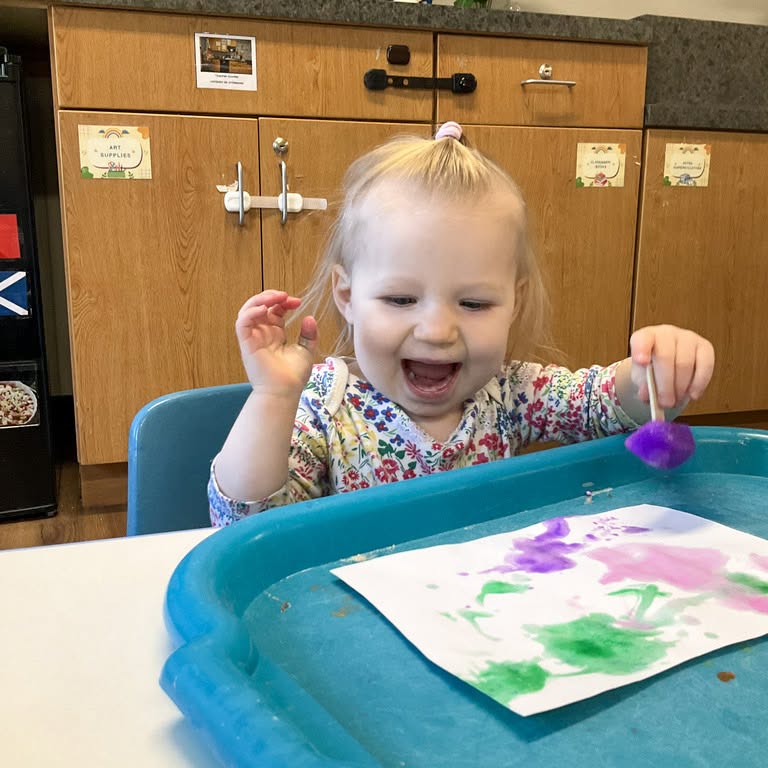 Child painting on paper with frozen paint ice sticks