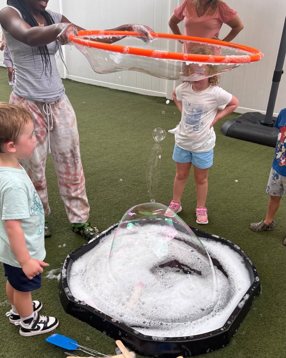 People making giant bubbles with a hula hoop and bubble solution tray
