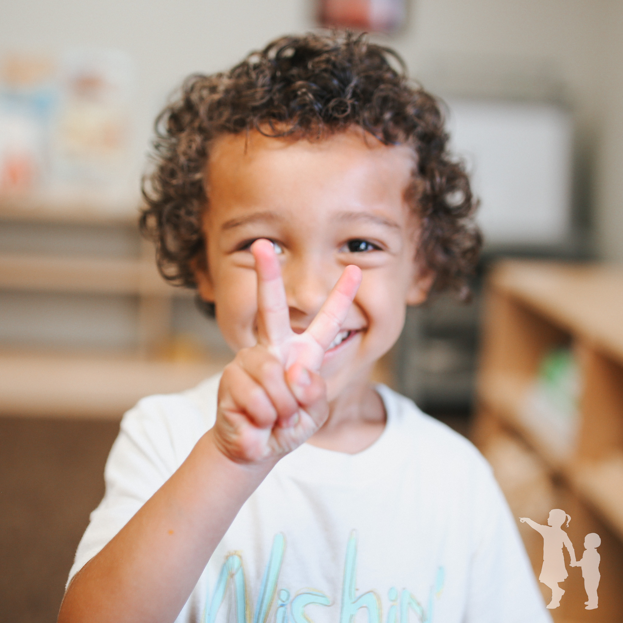Child with curly hair holding up two fingers