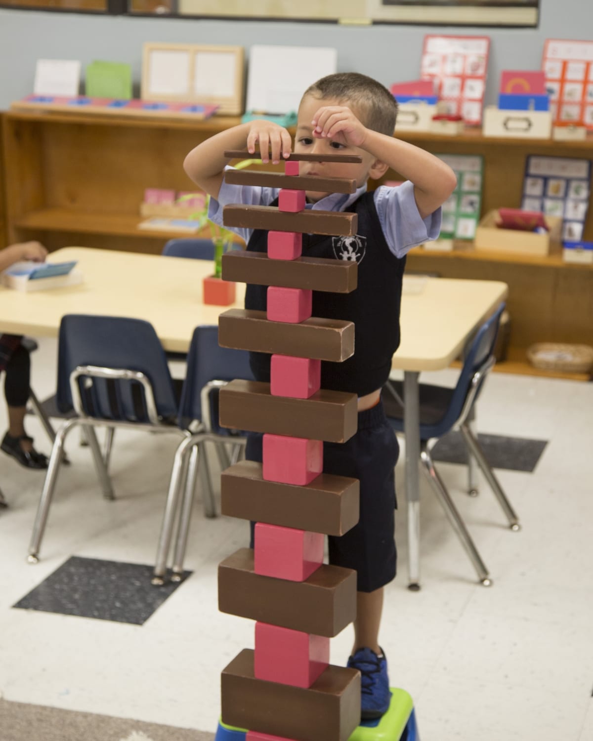 Child stacking large blocks in a classroom