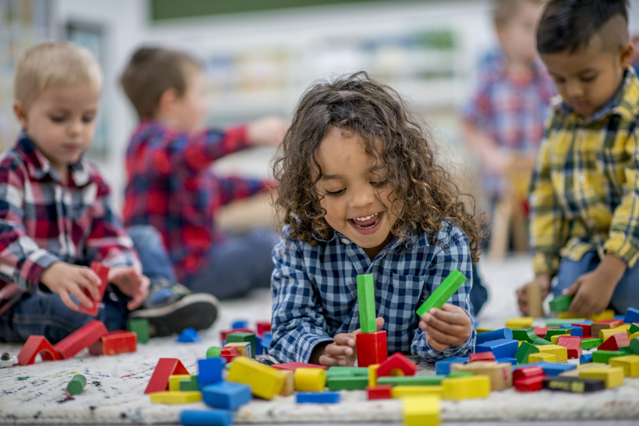 Child playing with colorful building blocks on the floor with other children