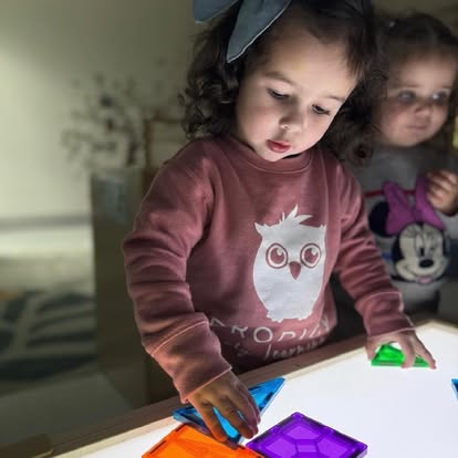 Child playing with colorful translucent blocks on a light table