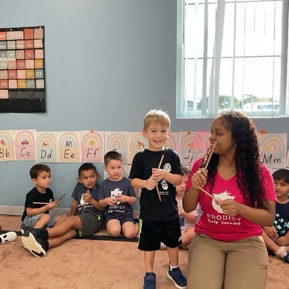 Adult and children in a classroom holding sticks