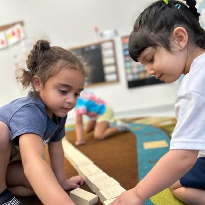 Two children playing with wooden blocks in a classroom