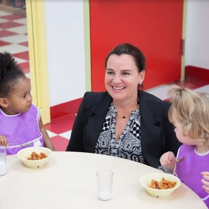 Person at a table with two children eating