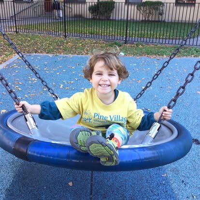 Child in a yellow shirt sitting in a swing at a playground