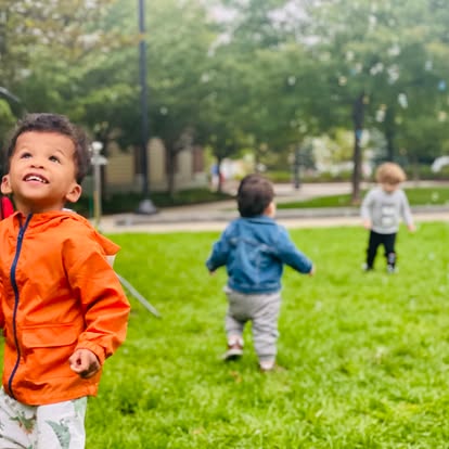 Three children playing on a grassy lawn