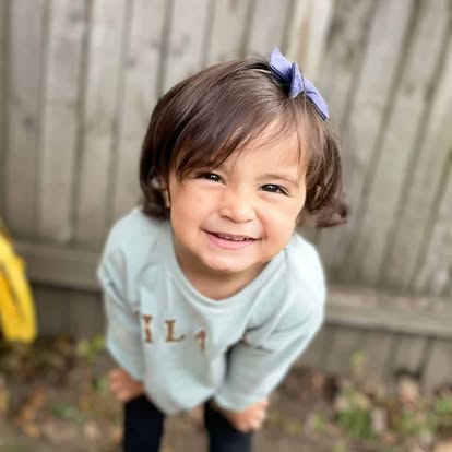 Child with a bow in their hair smiling