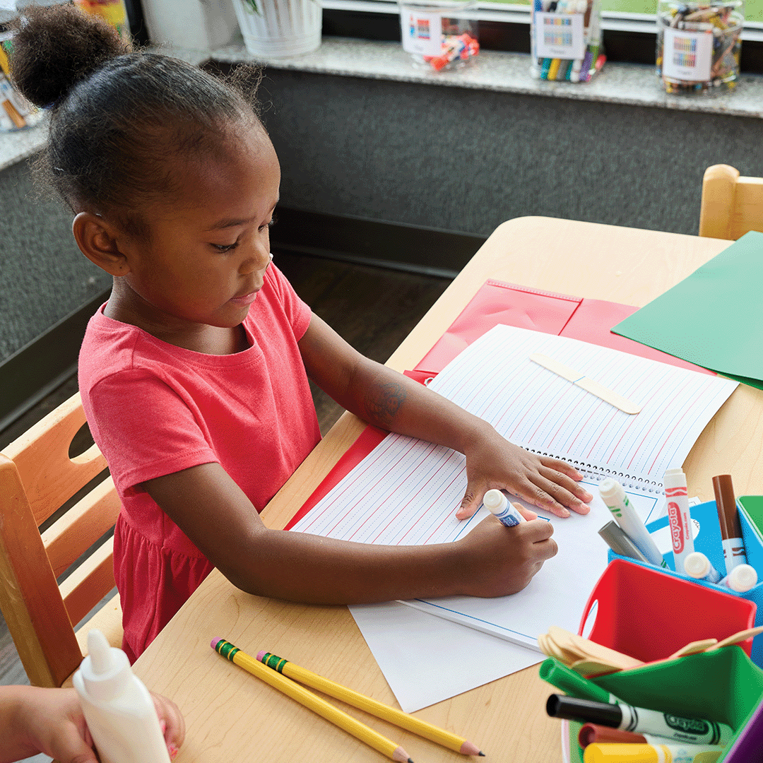 Child writing in a notebook at a table