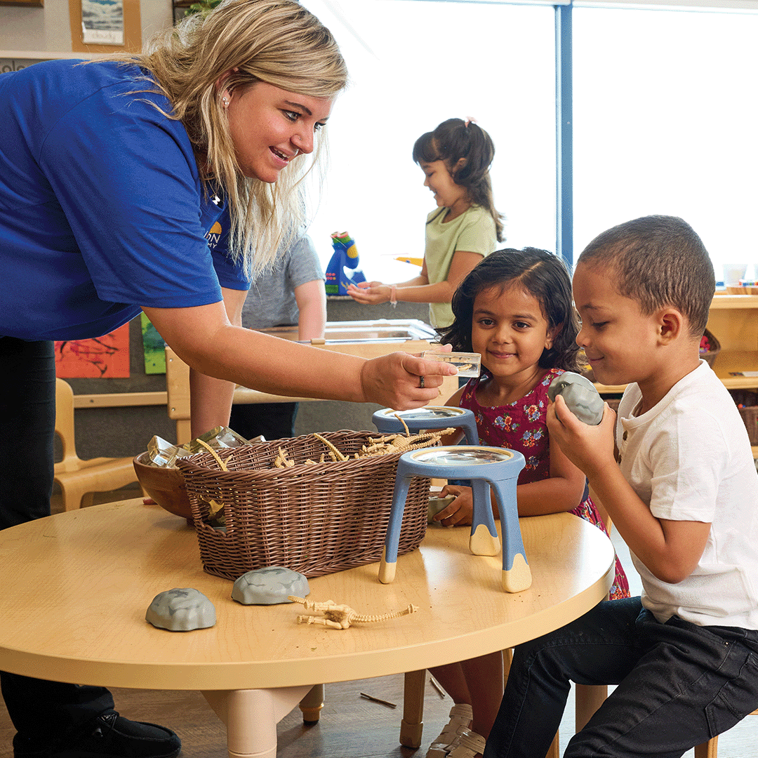 Adult and two children at a table with a basket and small objects