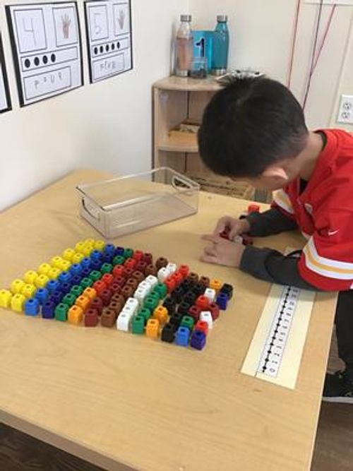 Child at a table playing with colorful connecting cubes