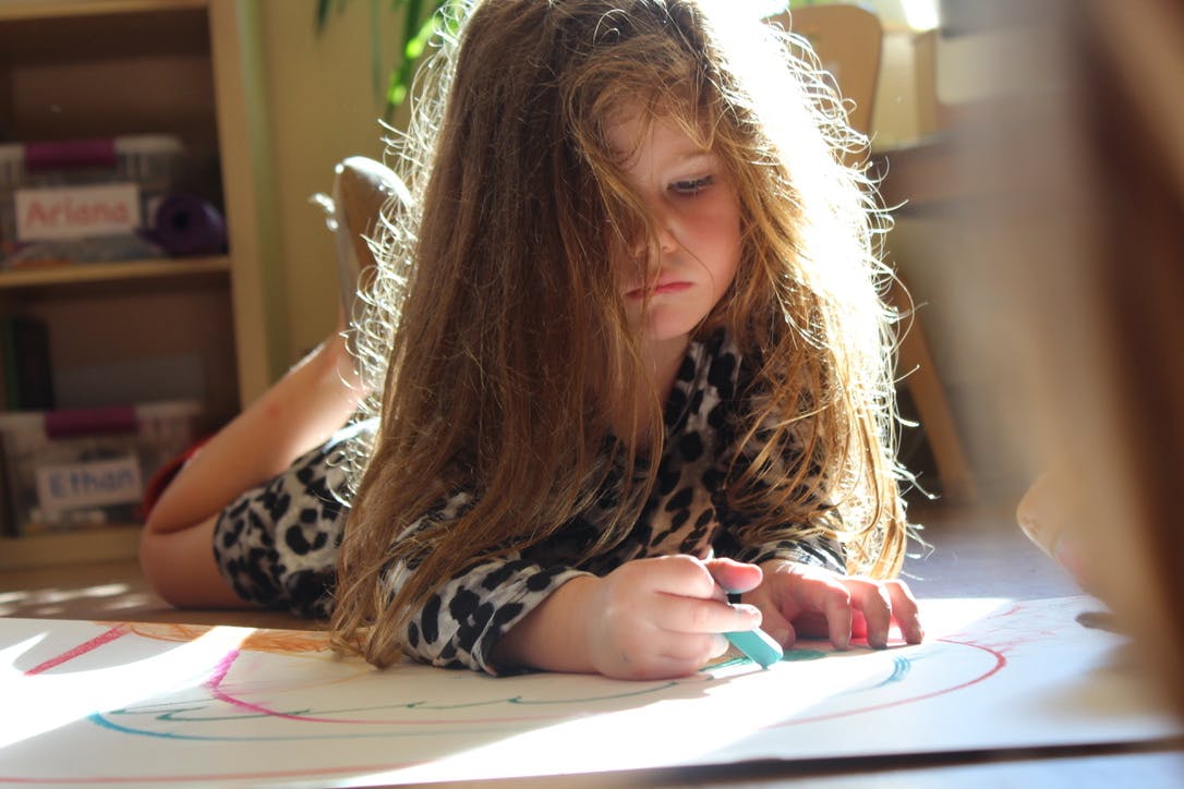 Child lying on floor drawing on paper