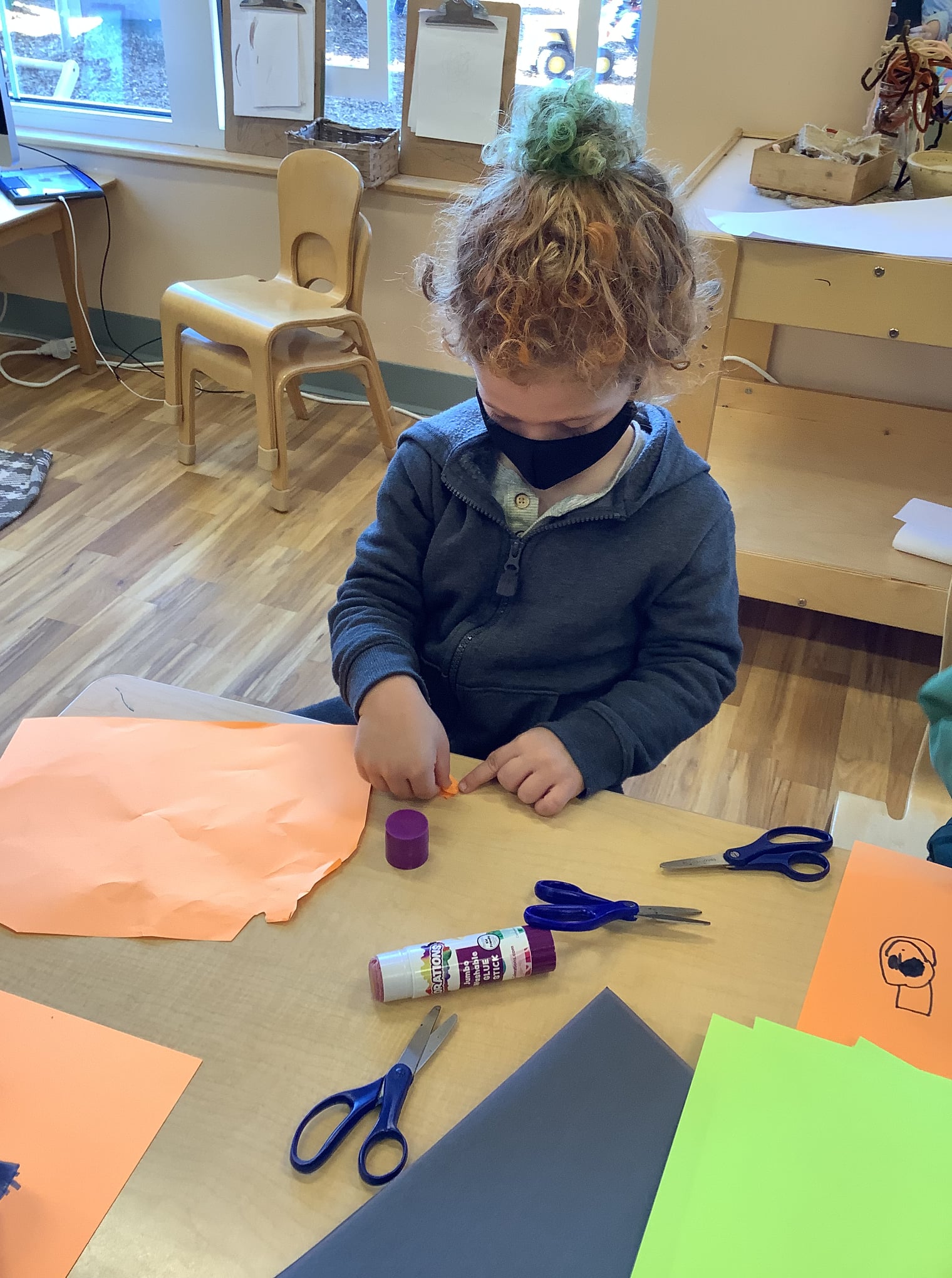 Child in a mask doing crafts at a table