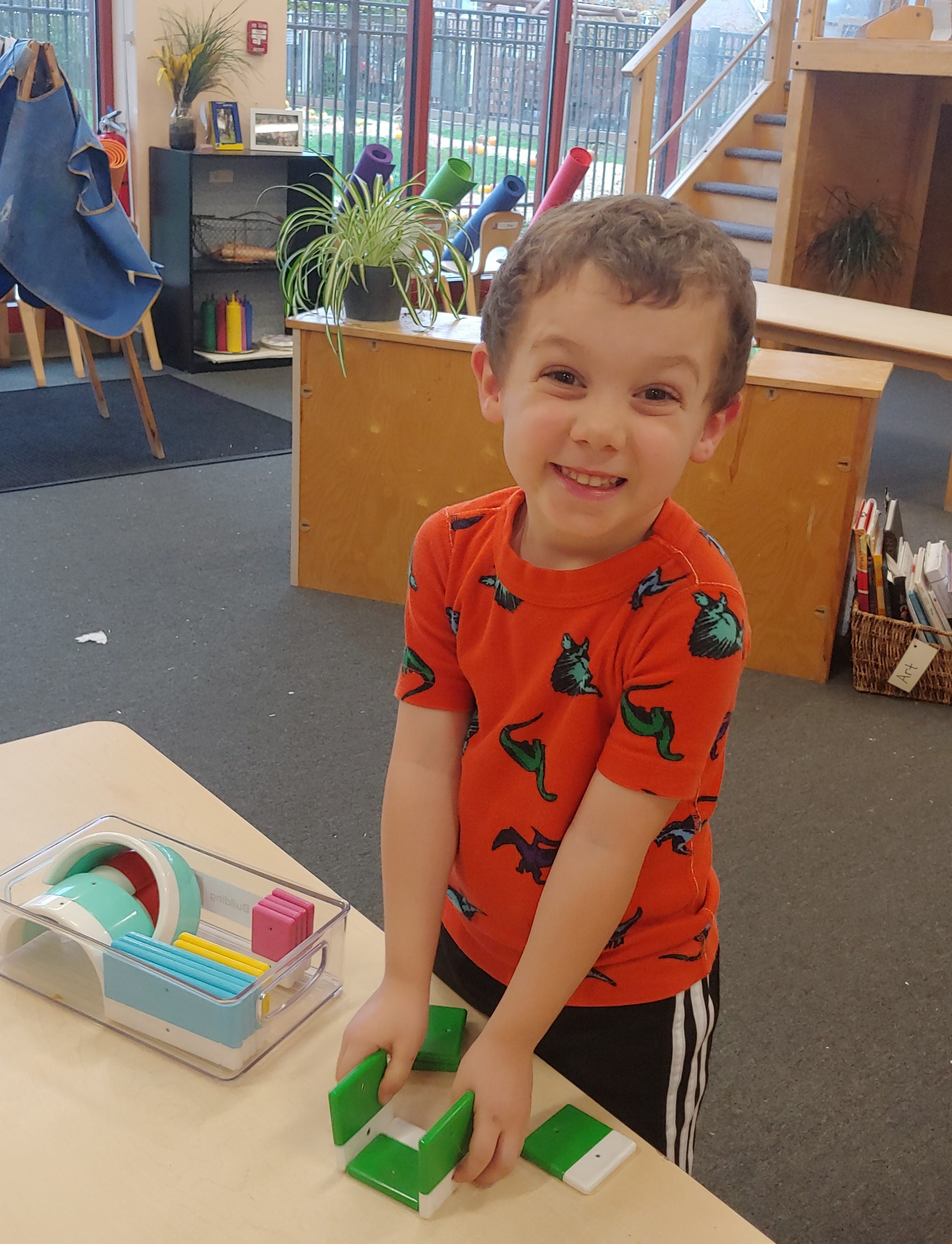 Child playing with green building blocks on a table