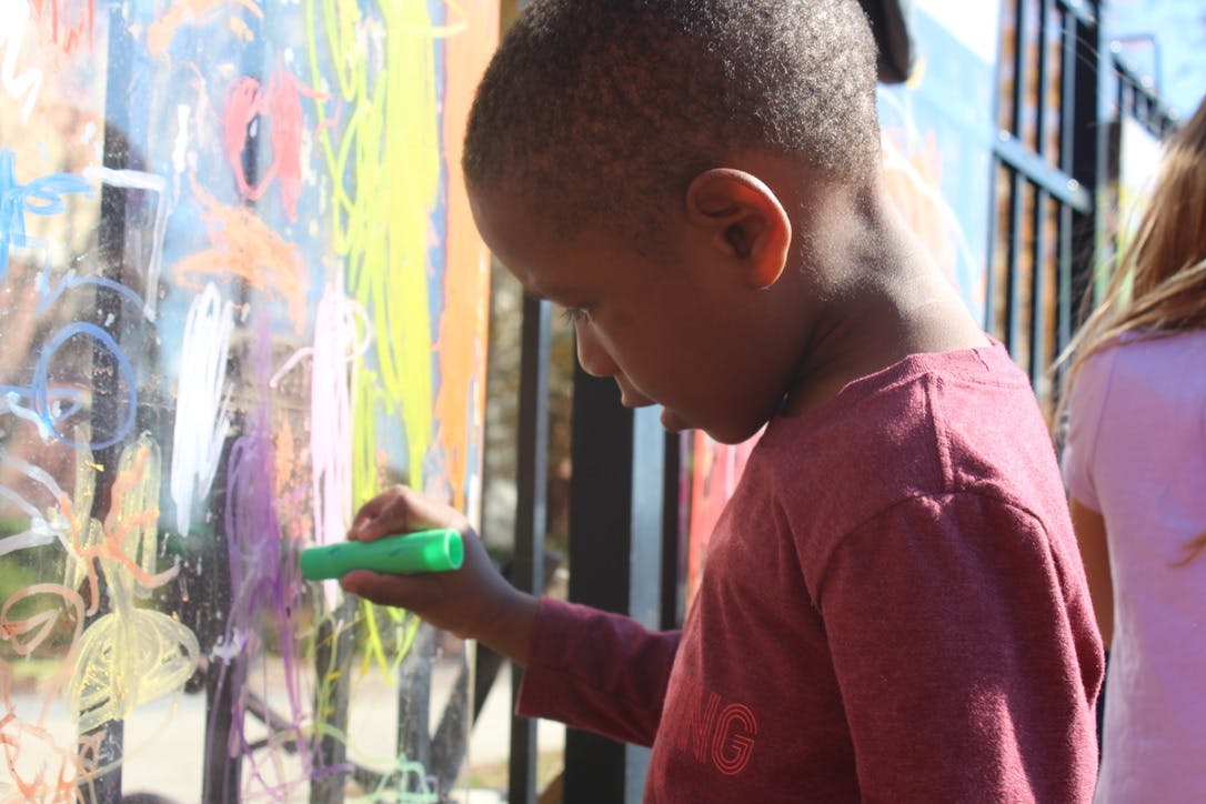 Child drawing on a clear surface with a green marker