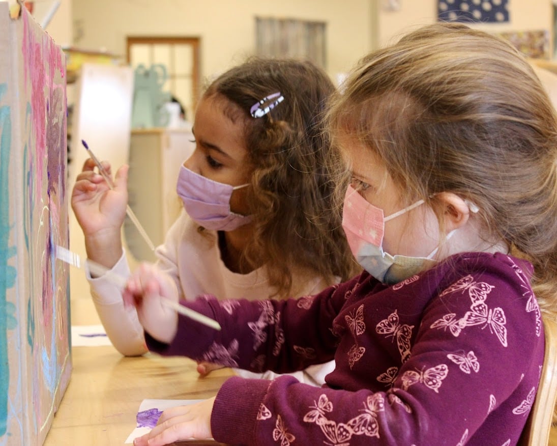 Two children in masks painting