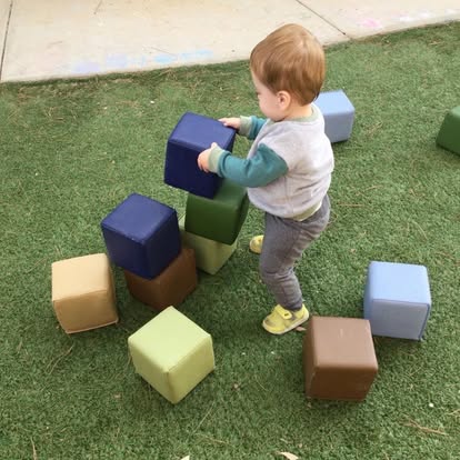 Child playing with foam cubes on grass
