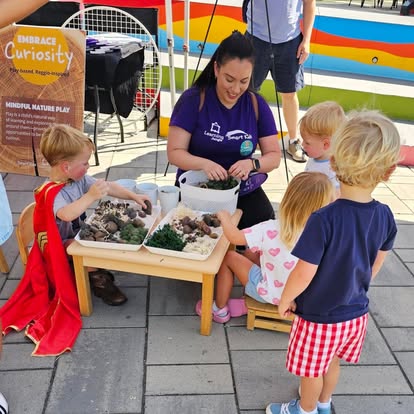 A person helping children play with natural materials at a small table