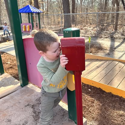 Child looking through a toy telescope on a playground