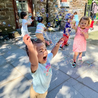 Children playing with soap bubbles outdoors on a stone patio